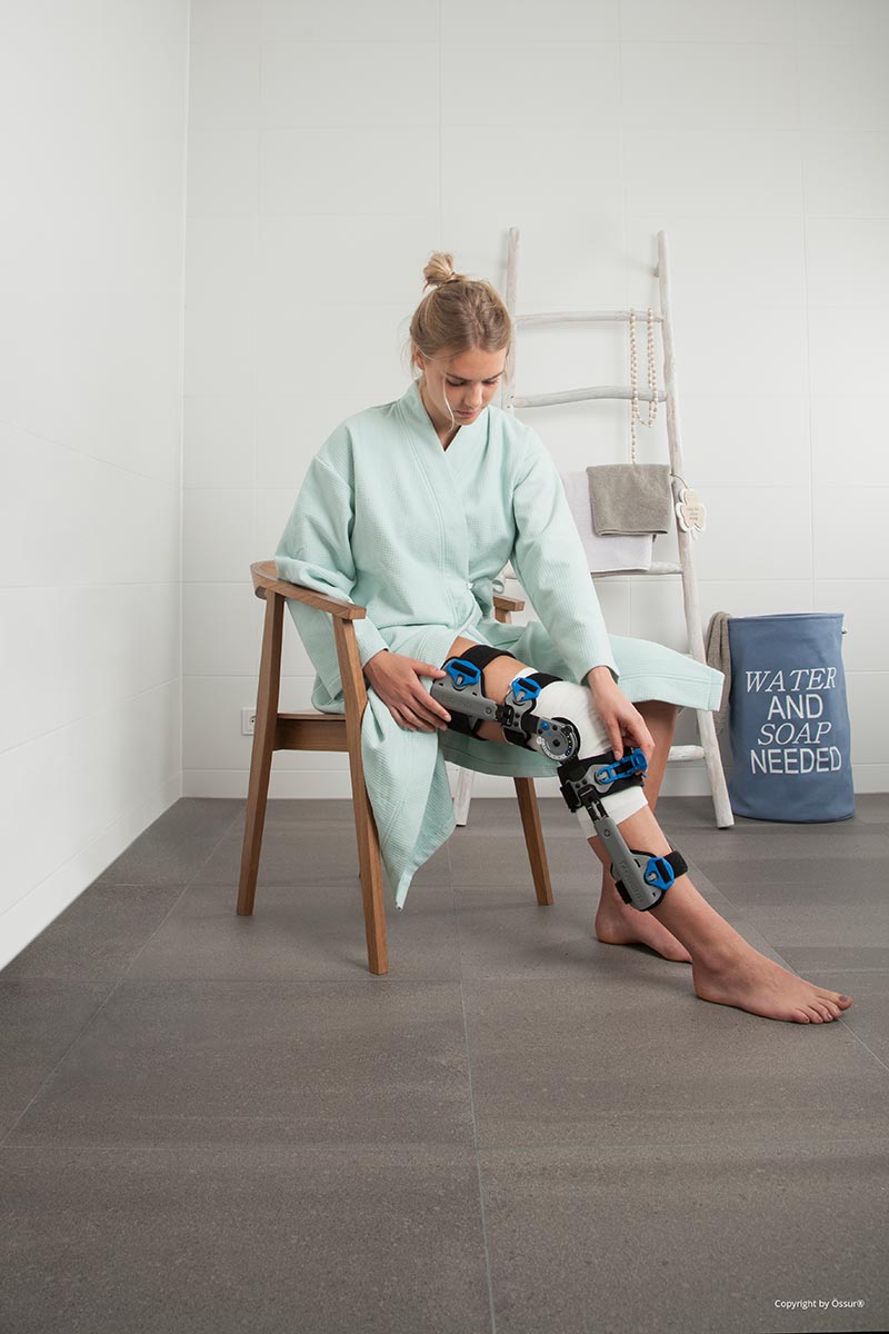 Foto einer sitzenden Frau mit Beinorthese